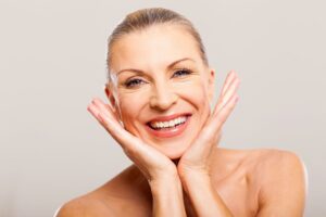 Woman with hands on face smiling at camera