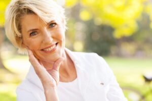 Woman at park in white shirt smiling at camera