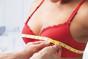 model in red bra measuring bust