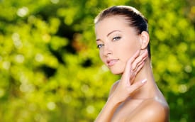 woman brushing hand across face in front of bush